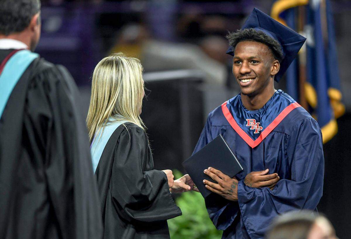 Marquise Henderson, right, smiles with Superintendent Jason Johns after getting his diploma from Principal Mary Boarts, during the Belton-Honea Path High commencement, where 260 graduated at the 6 p.m. ceremony in Clemson, S.C. Thursday, May 15, 2025. Henderson, who finished BHP High in December 2024, was an early enrollee at Clemson University and started practicing with the Tigers football team, but came back to join in the ceremony with his high school.
