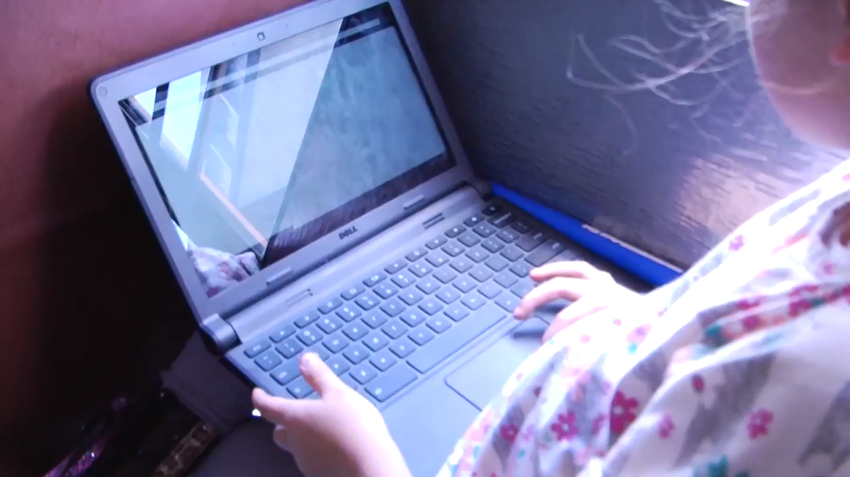 A student uses her laptop while riding on a Google Rolling Study Hall bus.