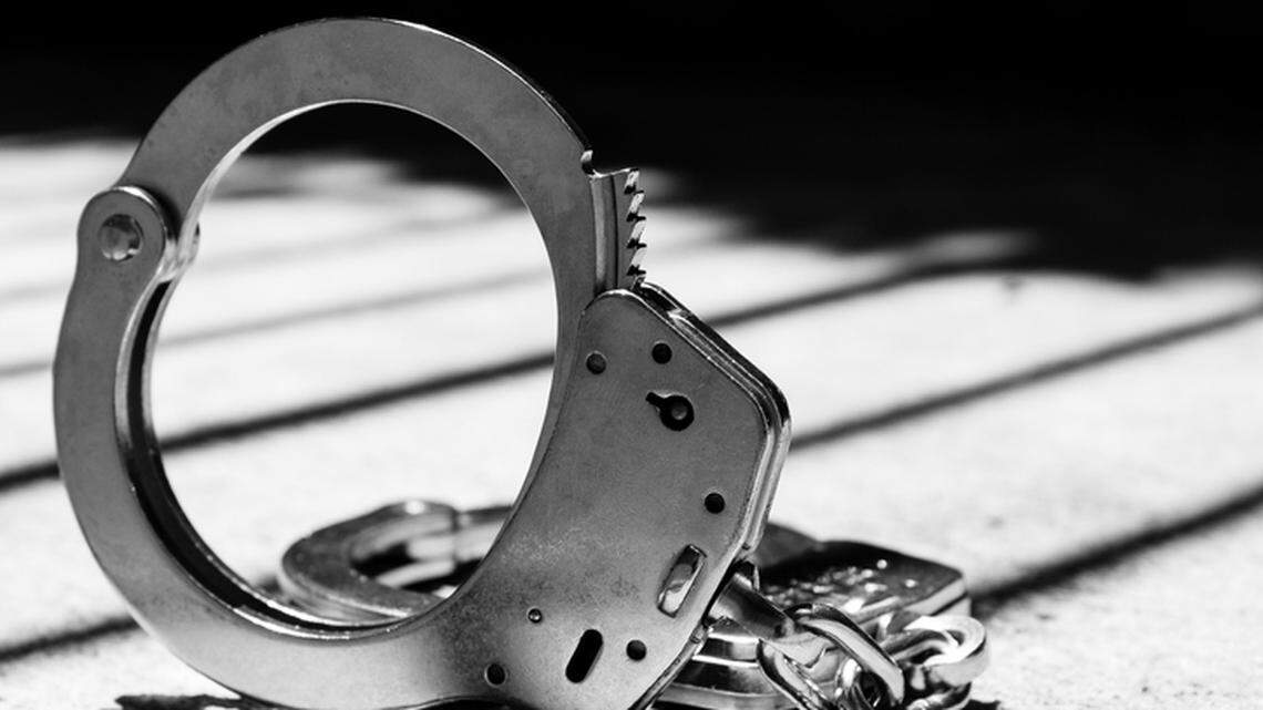 DUI or Criminal Handcuff with Bars Behind in Shadows