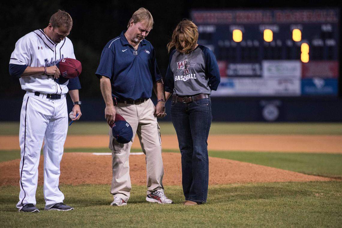 Nathan and Laurie Williams, parents of Brett Williams, with White Knoll head coach Charles Assey, participate in a moment of silence honoring their son before a preseason game against Newberry at White Knoll High School Wednesday, March. 1, 2017, in Lexington, S.C.