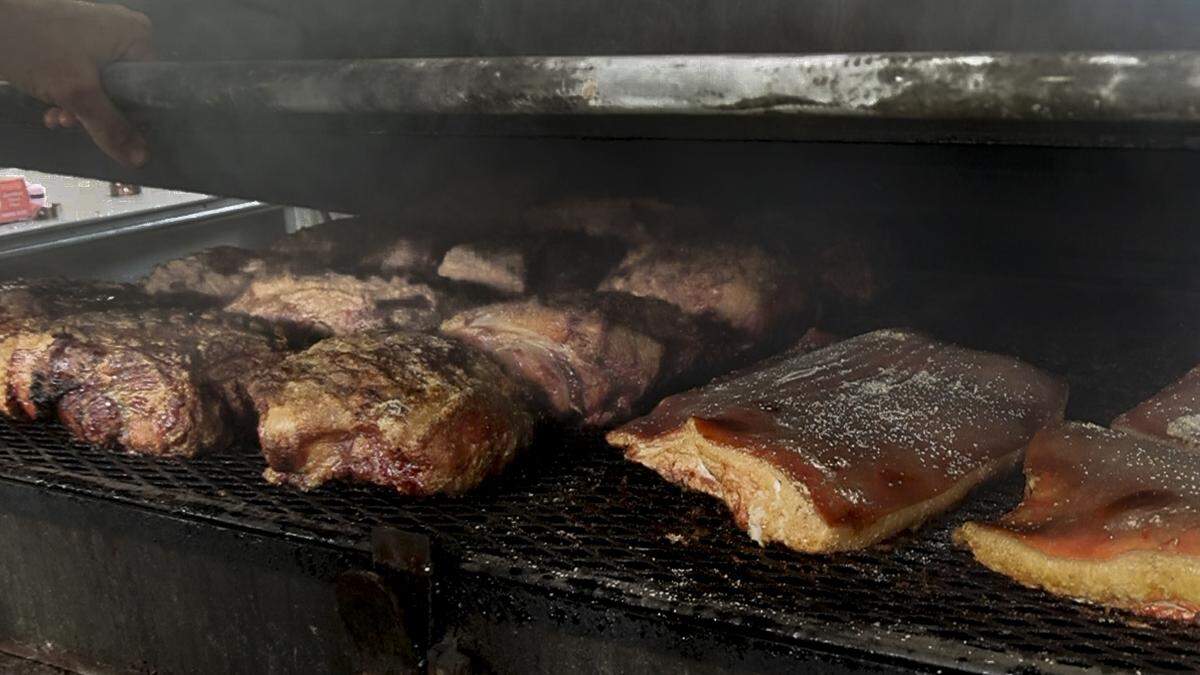 Pork shoulder and pork belly cook over hot coals at City Limits Barbeque restaurant in West Columbia. 