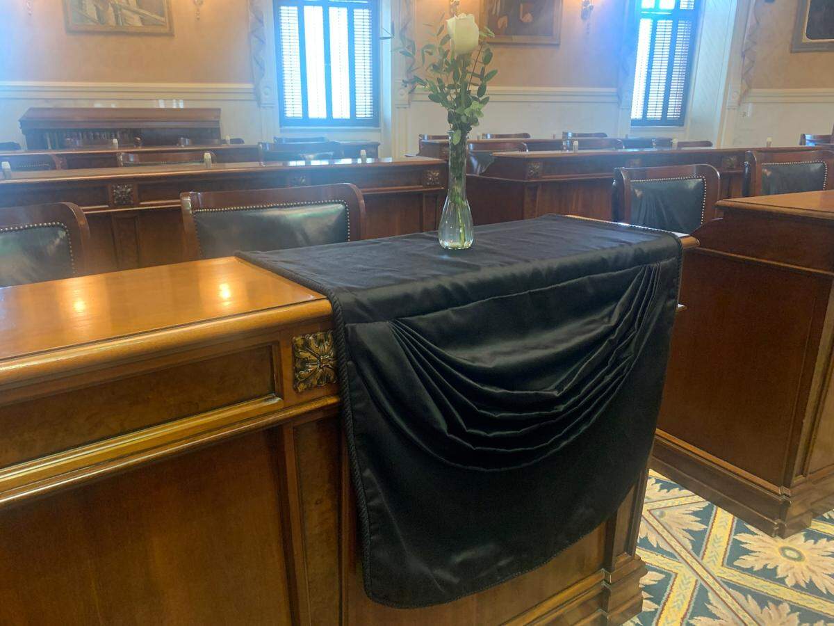 As people mourn state Sen. John Scott’s death, his desk in the Senate chamber is draped in black sheet with a single flower in a vase placed on top.