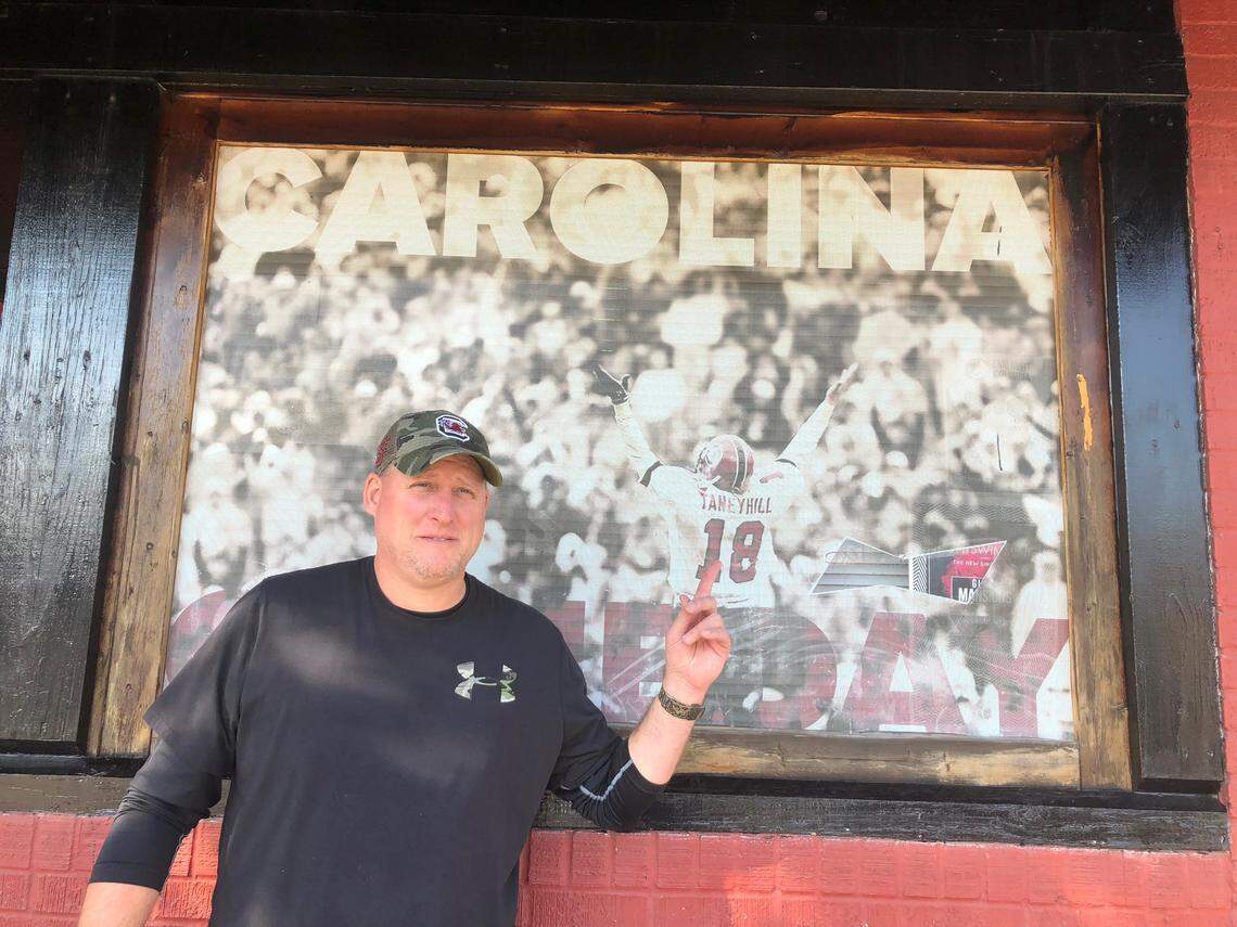 Former South Carolina quarterback Steve Taneyhill poses with a younger form of his self outside Taneyhill’s Group Therapy Bar in Five Points.