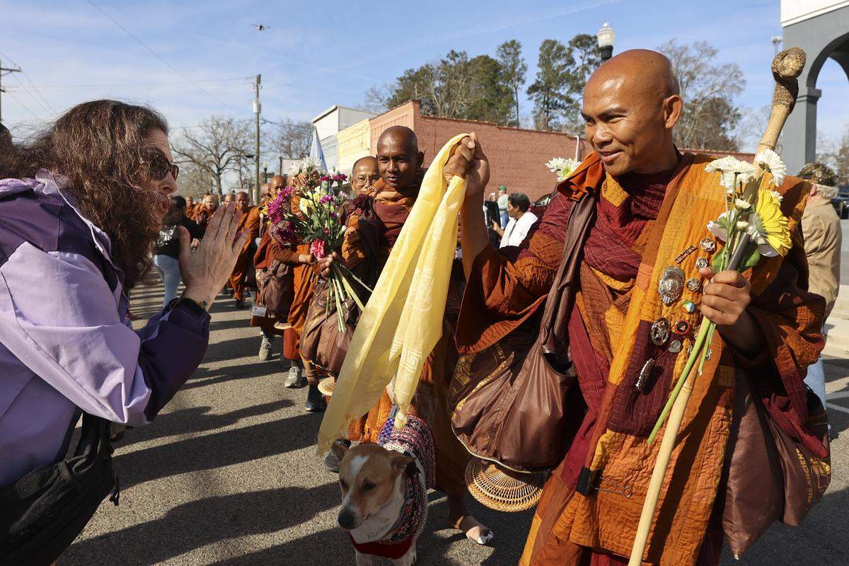Amy Jackson of Hendersonville, N.C. bows after presenting a Tibetan Buddhist amulet called a kata to the Venerable Bhikkhu Pannakara as the monks with the Walk for Peace arrive in Saluda, SC, on Thursday, Jan. 8, 2026.