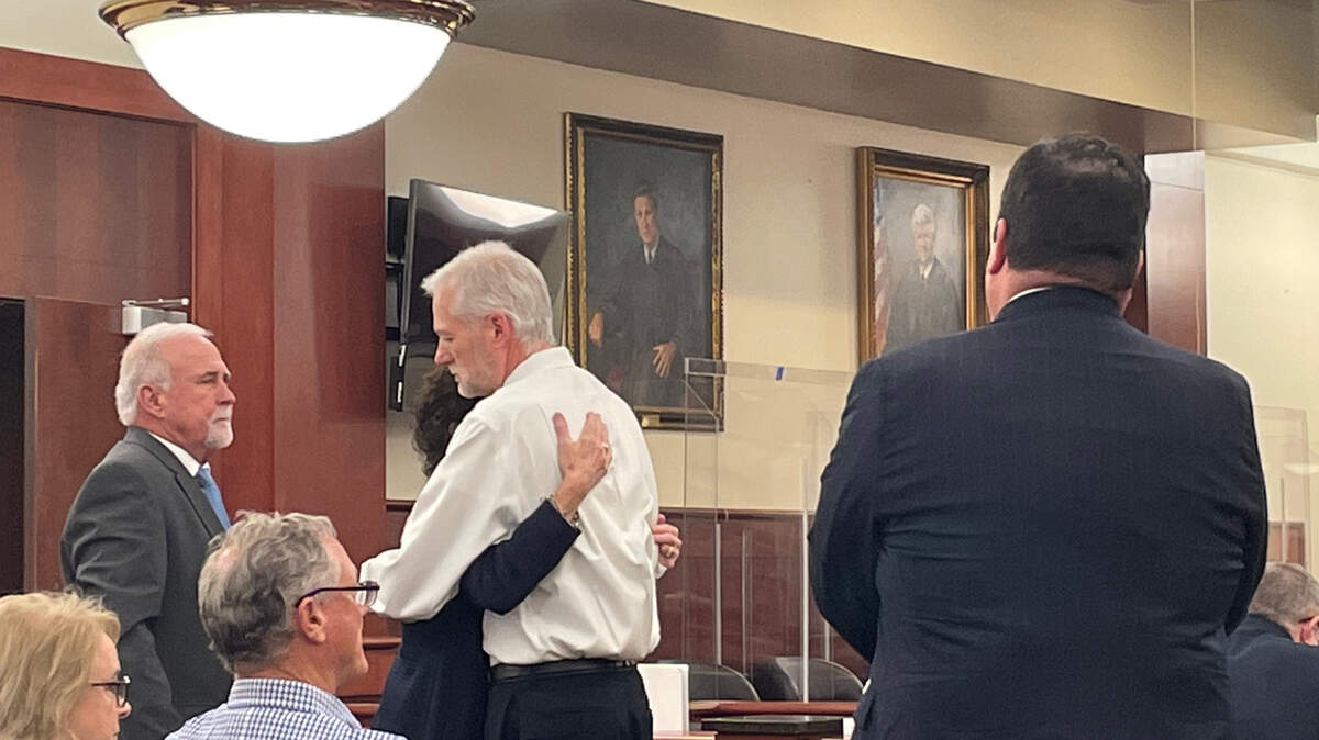 William Player Holland’s father stands with his wife who hugs a prosecutor during the criminal case for their son’s death.