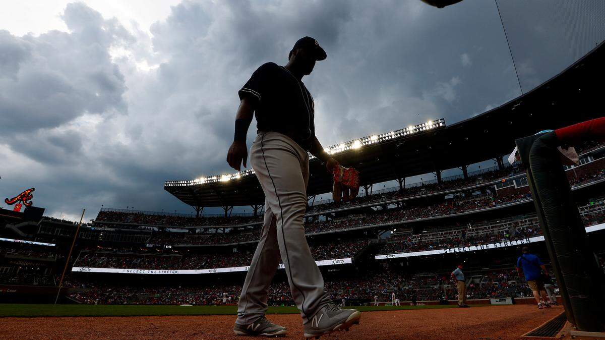San Diego Padres center fielder Franmil Reyes (32) walks to the dugout ss dark clouds hang over SunTrust Park after the third inning of a baseball game against the Atlanta Braves, Saturday, June 16, 2018, in Atlanta.