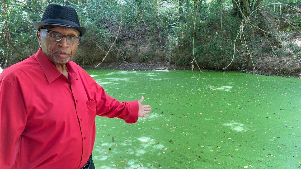 The Rev. Aaron Walker is among Saluda County residents distraught that pollution turned a popular clear-running creek into a slimy, foul-smelling stream with unsafe levels of bacteria last summer.  Mine Creek is downstream from a dog food plant that is under state investigation. In this photo, taken Aug. 10, 2023, Walker points out the scum that has clogged the creek since May.