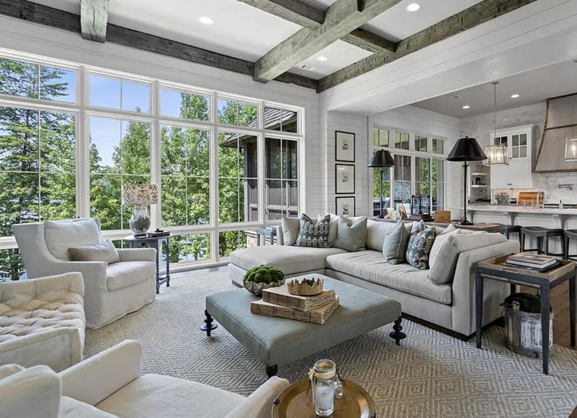 The house has antique French stone and beams in the great room, which has oversized windows and transoms overlooking the lake.