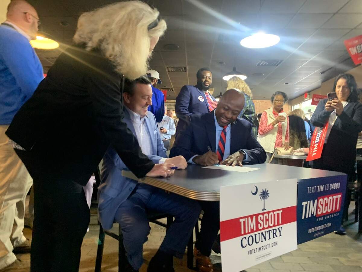U.S. Sen. Tim Scott, R-South Carolina, (right) signs paperwork Monday, Oct. 16, 2023, at Doc’s Barbecue, to run in the 2024 S.C. Republican Presidential Primary.