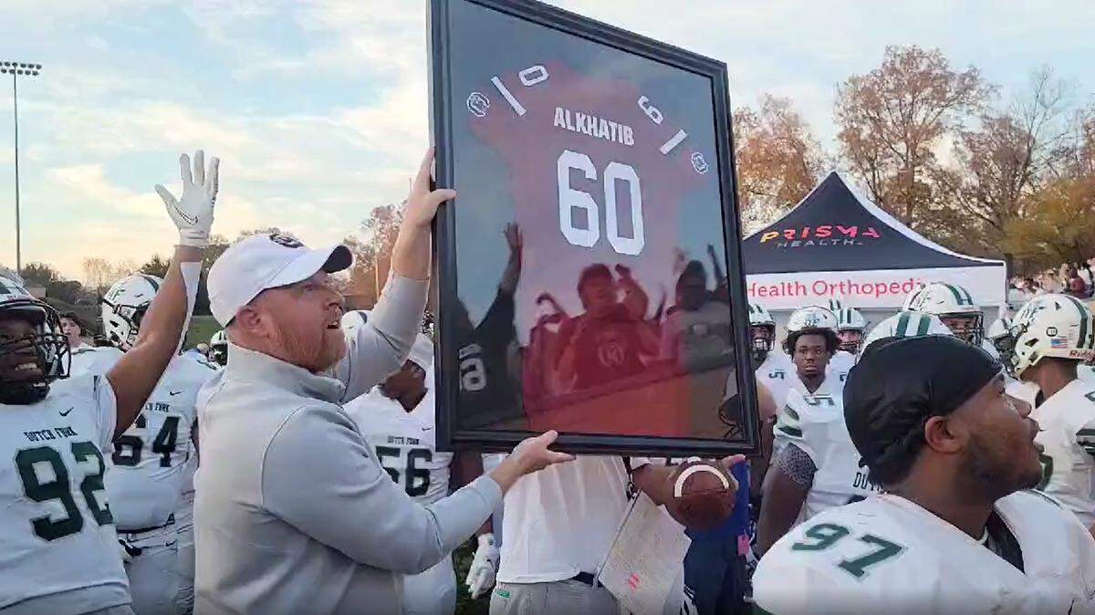 Erik Kimrey presents Kelly Alkhatib with a No. 60 Gamecocks jersey before the Dutch Fork game Saturday.