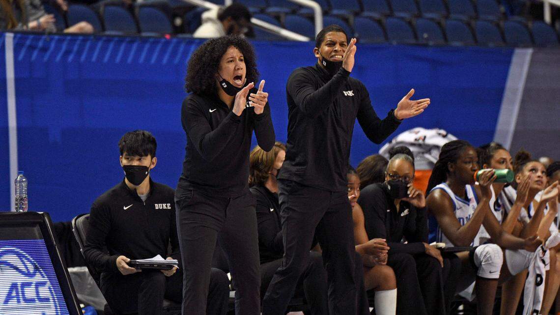 Duke Blue Devils head coach Kara Lawson and assistant coach Winston Gandy cheer on the team during the 2022 ACC Tournament at the Greensboro Coliseum.