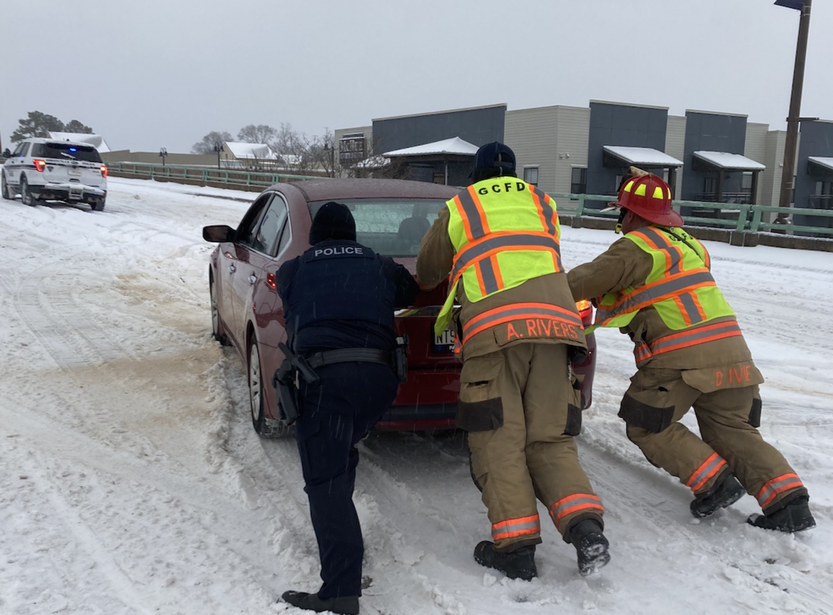 Members of Greenville City Fire Department at Greenville Police Department help a stranded motorist on the Church Street bridge in downtown Greenville.