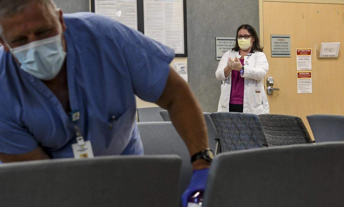 Infection Preventionist Carlye Gilbert, BSN, RN, background, applies hand sanitizer in the lobby of Hardeeville’s Coastal Carolina Hospital on Wednesday, April 29, 2020 as endoscope tech Mark Thomas wets down the furniture to reduce the spread of the coronavirus. Gilbert said since procedures were placed on standby, and to minimize the use of much needed personal protective equipment, staff were cross trained to perform ancillary duties such as housekeeping and symptom screenings.