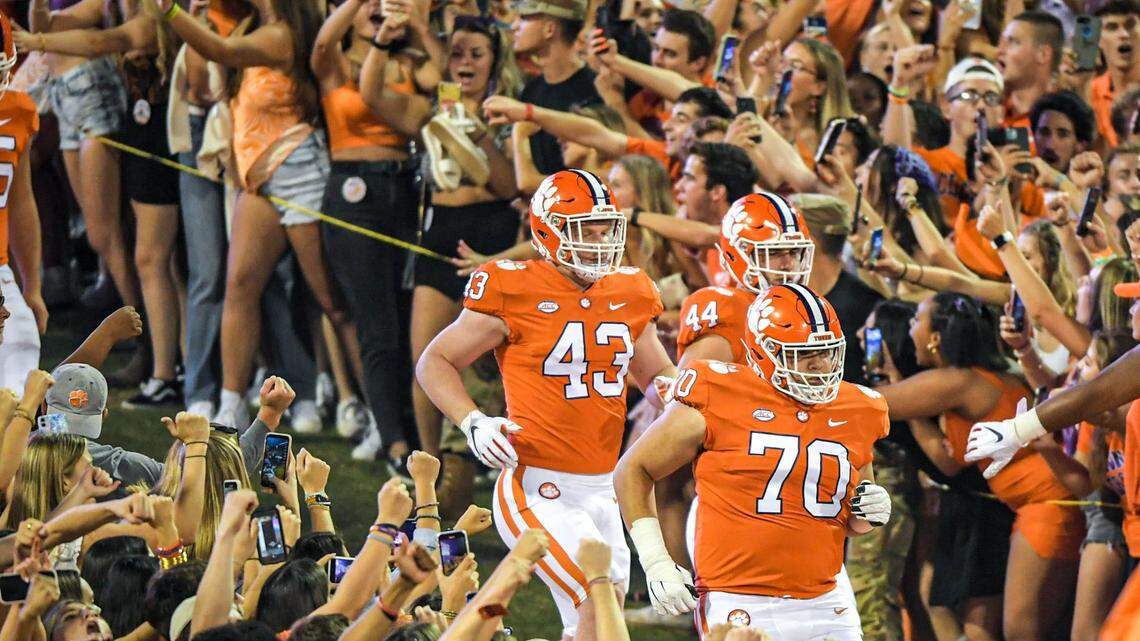 Clemson players run down the hill before a college football game.