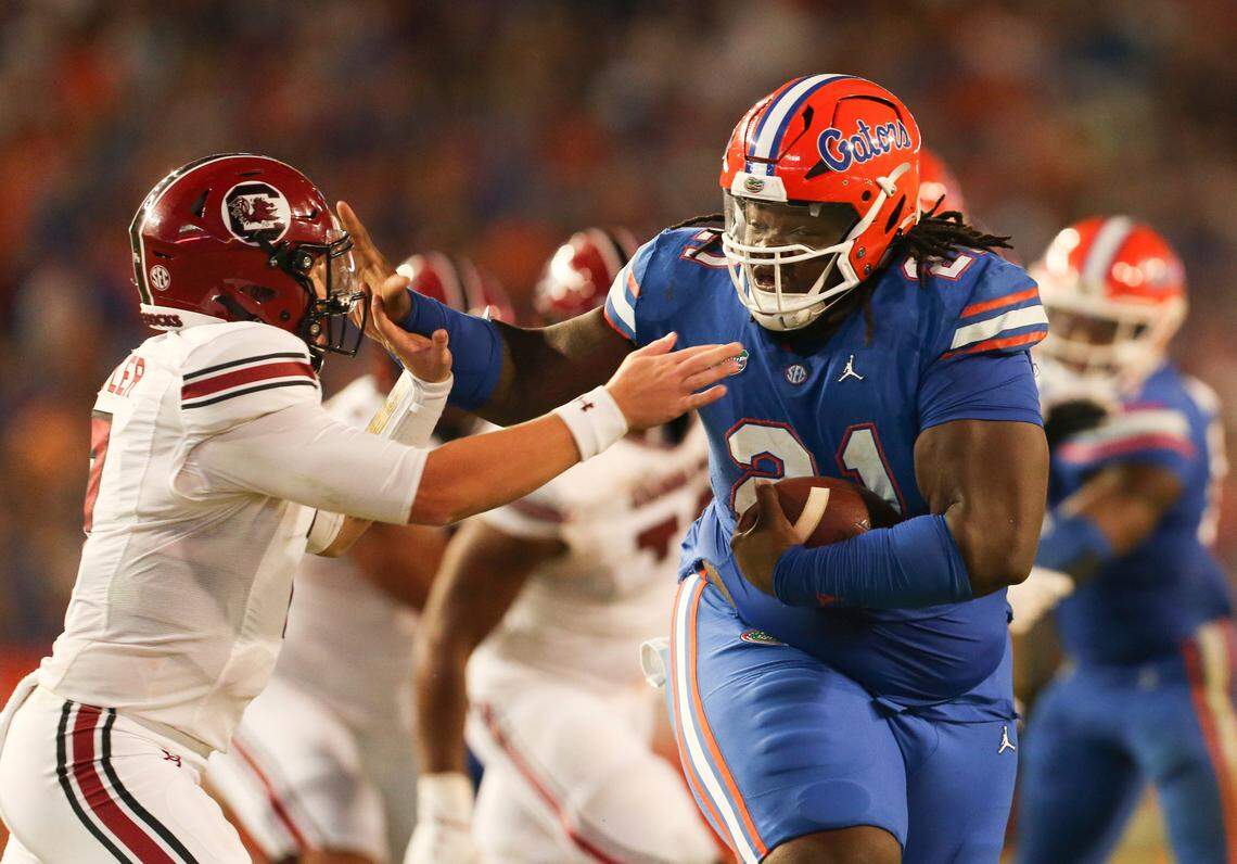 Florida defensive lineman Desmond Watson (21) stiff arms South Carolina quarterback Spencer Rattler (7) after recovering a fumble during the second half of an NCAA college football game, Saturday, Nov. 12, 2022, in Gainesville, Fla.