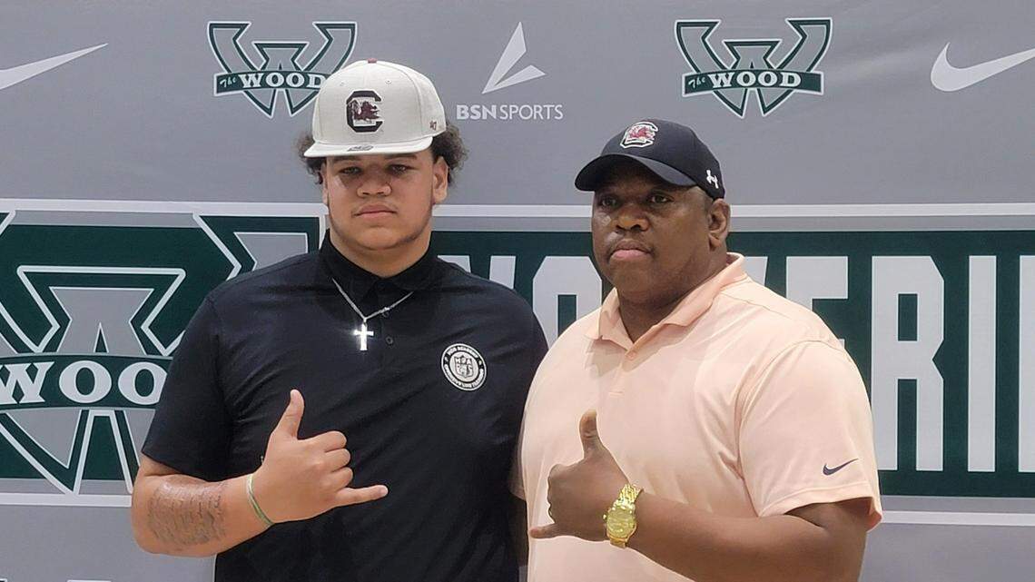 Woodland High’s Kam Pringle, left, poses for a photo with his father after announcing his commitment to the South Carolina football team.
