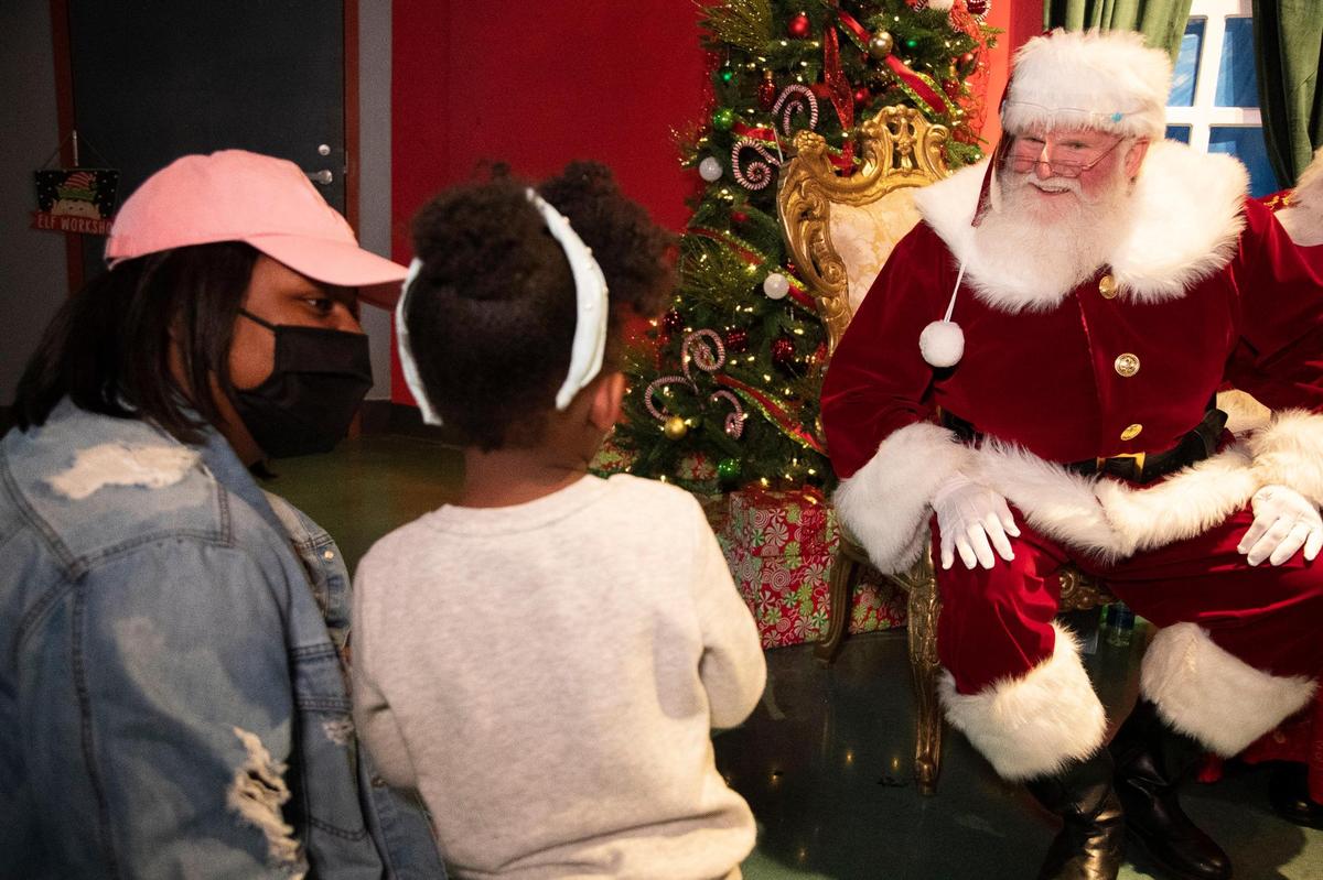 Harlem Grady, 2, and her mother Chrissy Grady speak with Santa and Mrs. Claus at EdVenture in Columbia, South Carolina on Saturday, December 12, 2020. EdVenture has placed a plexiglass barrier between visitors and Santa Claus so families can take pictures with Santa Claus without wearing masks.