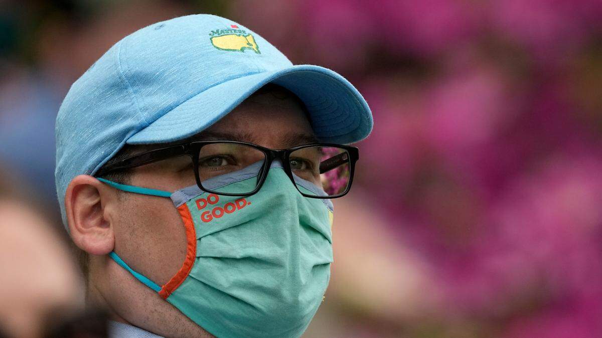 A masked spectator watches play on the 15th hole during the third round of the Masters golf tournament on Saturday, April 10, 2021, in Augusta, Ga. (AP Photo/Charlie Riedel)