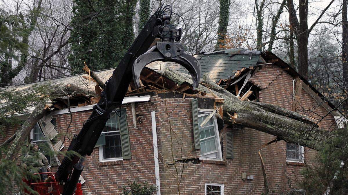 Workers attempt to remove a tree after it fell on a house in Winston-Salem, N.C., Sunday, Jan. 13, 2019, An ice storm coated central North Carolina, toppling numerous trees and leaving thousands without power. (AP Photo/Skip Foreman)