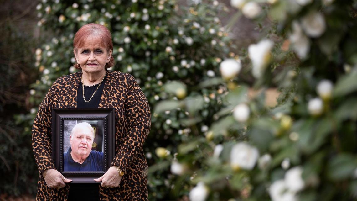 Karen Lovette poses for a portrait holding a photograph of her husband Al Lovette in Camden, South Carolina on Tuesday, March 2, 2021. To protect her and others from the coronavirus, Karen was not able to be near her husband after he died.