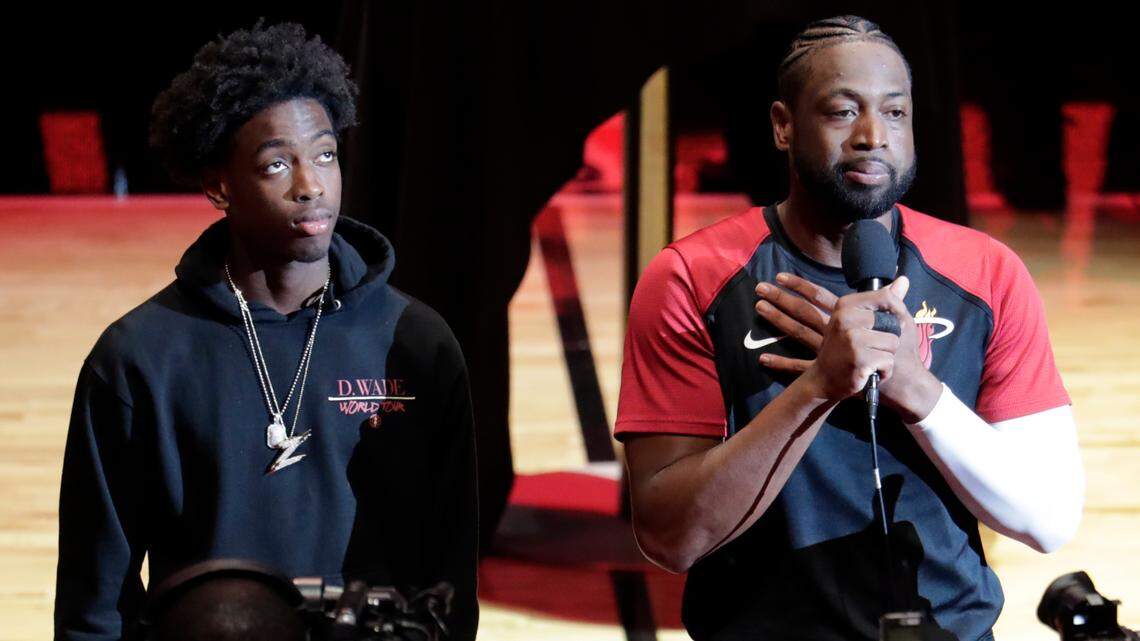 Miami Heat guard Dwyane Wade, right, speaks as his son Zaire, left, looks on during a ceremony honoring Wade who is playing his final home regular season game when the Heat host the Philadelphia 76ers, Tuesday, April 9, 2019, in Miami. Wade is retiring at the end of the season. (AP Photo/Lynne Sladky)