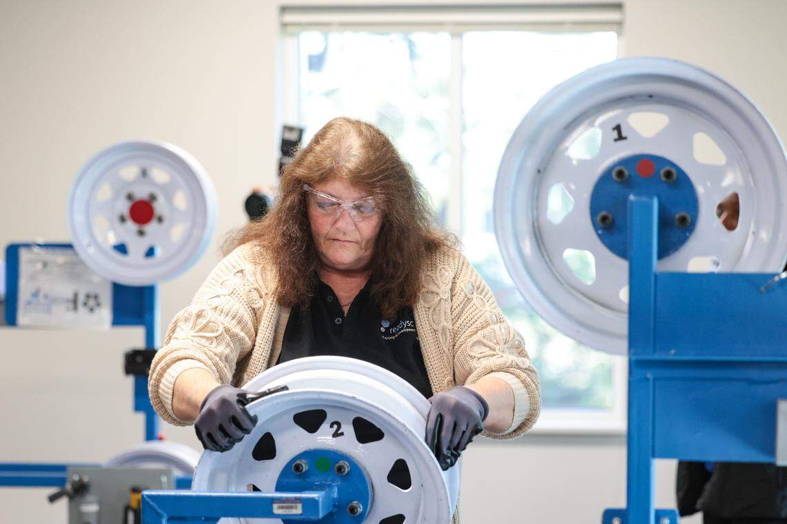 ReadySC instructor Cynthia Tedder demonstrates the use of a wheel assembly station in the new training area at the Cornerstone Economic Development and Workforce Training Center at Midlands Technical College. The center is being used to screen applicants for Scout Motors.