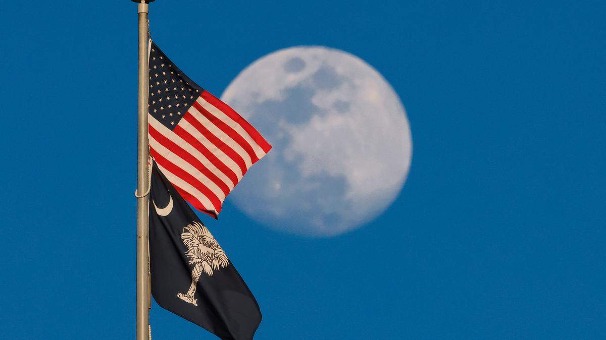 The moon rises behind the South Carolina statehouse dome flags in Columbia, S.C. on Tuesday, March 11, 2025. (Travis Bell/STATEHOUSE CAROLINA)