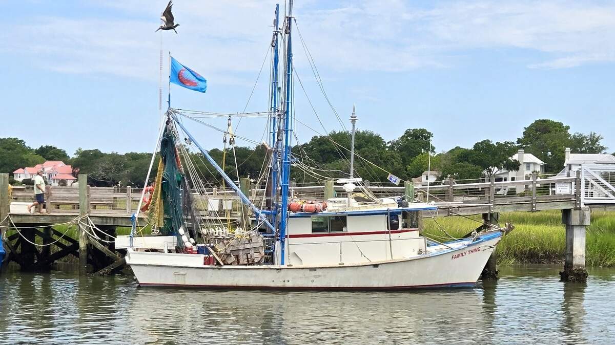 A small shrimp trawler sits alone on a dock July 12, 2025 in Mount Pleasant, South Carolina near Shem Creek.