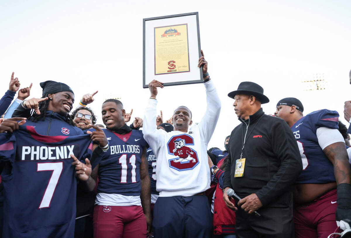South Carolina State head coach Chennis Berry hoists up a framed invitation to the Cricket Celebration Bowl following South Carolina State’s game against Norfolk State at Oliver C. Dawson Stadium in Orangeburg on Saturday, November 23, 2024.