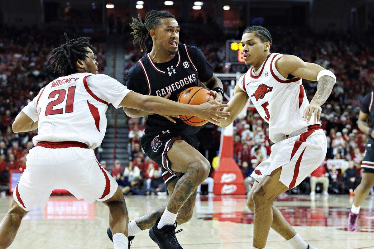 Meechie Johnson #5 of the South Carolina Gamecocks goes to the basket in the second half against Darius Acuff Jr. #5 and D.J. Wagner #21 of the Arkansas Razorbacks at Bud Walton Arena on January 14, 2026 in Fayetteville, Arkansas.