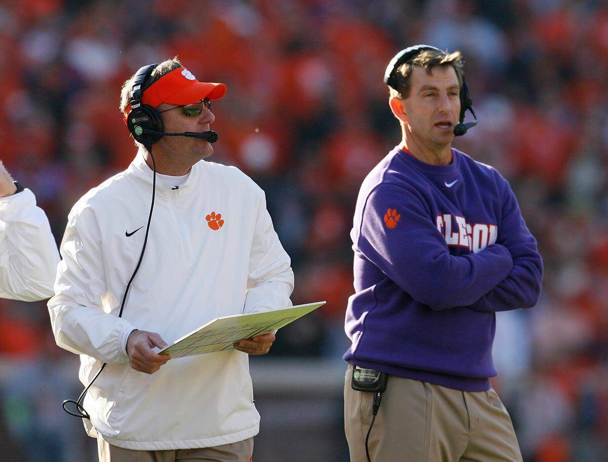 Offensive Coordinator Chad Morris of the Clemson Tigers and Head Coach Dabo Swinney look on during their game against the South Carolina Gamecocks at Memorial Stadium on November 29, 2014 in Clemson, South Carolina.