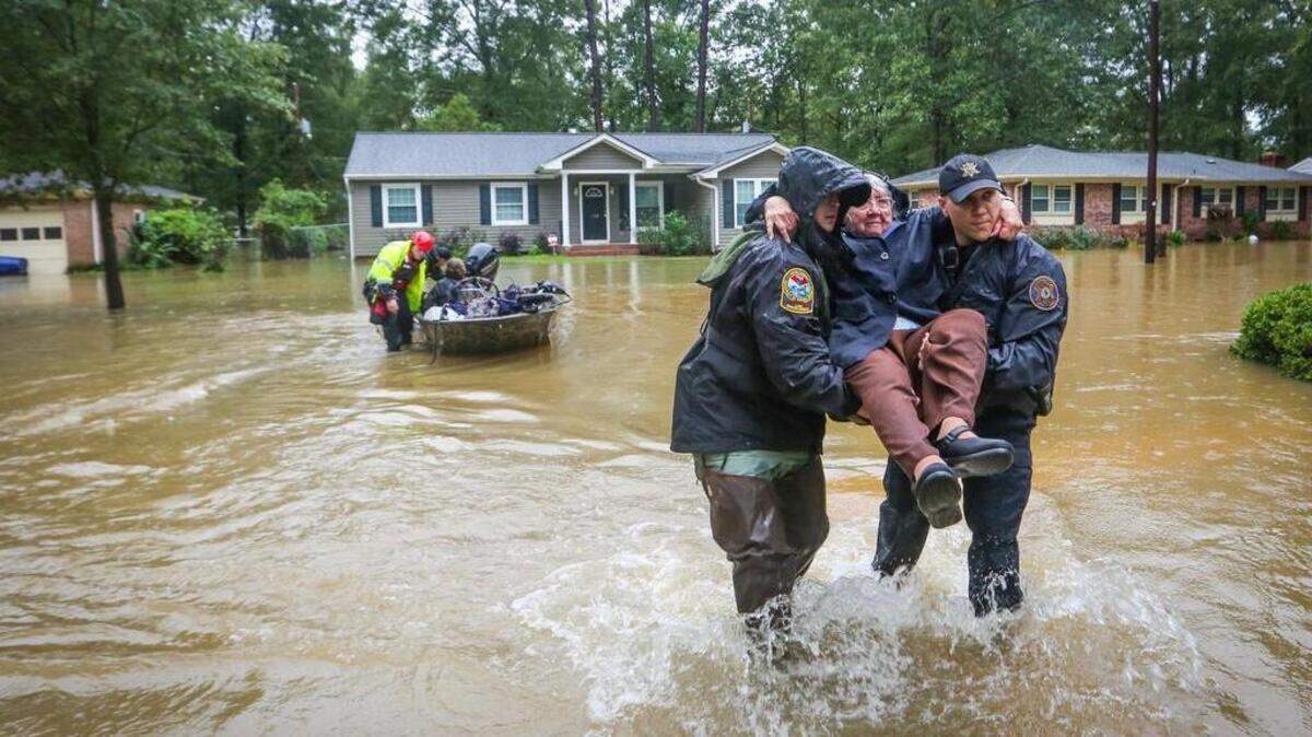 DNR officer Brett Irvin and Lexington Co. Deputy Dan Rusinyak carry June Loch to dry land after she was rescued from her home in the Pine Glen subdivision off of Tram road in the St. Andrews area of Columbia. Residents are having to abandon their homes because of flooding coinciding with release of water from the dam. 10/5/15