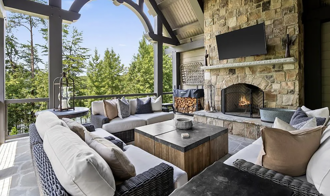 The fireplace is made of antique French stone and beams in the great room, which has oversized windows and transoms overlooking the lake.&nbsp;