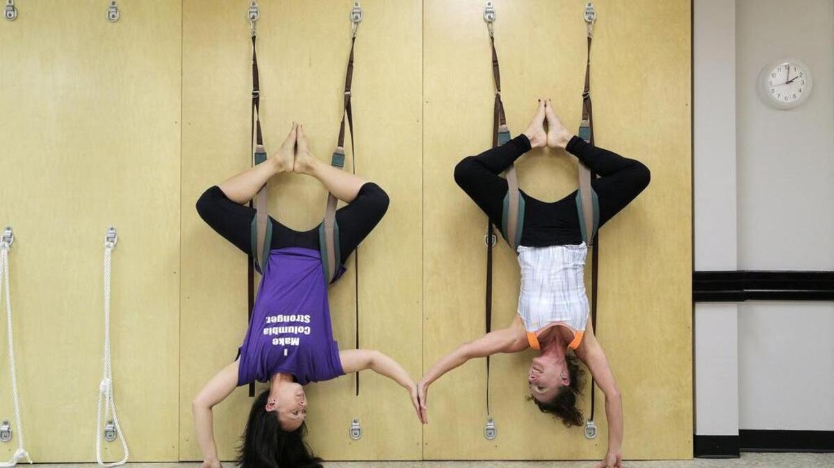 Fit Columbia owner Angela Yong, left, and Anne Miller demonstrate yoga poses on the wall at Fit Columbia. Bungee yoga will be offered at the Blossom street location.