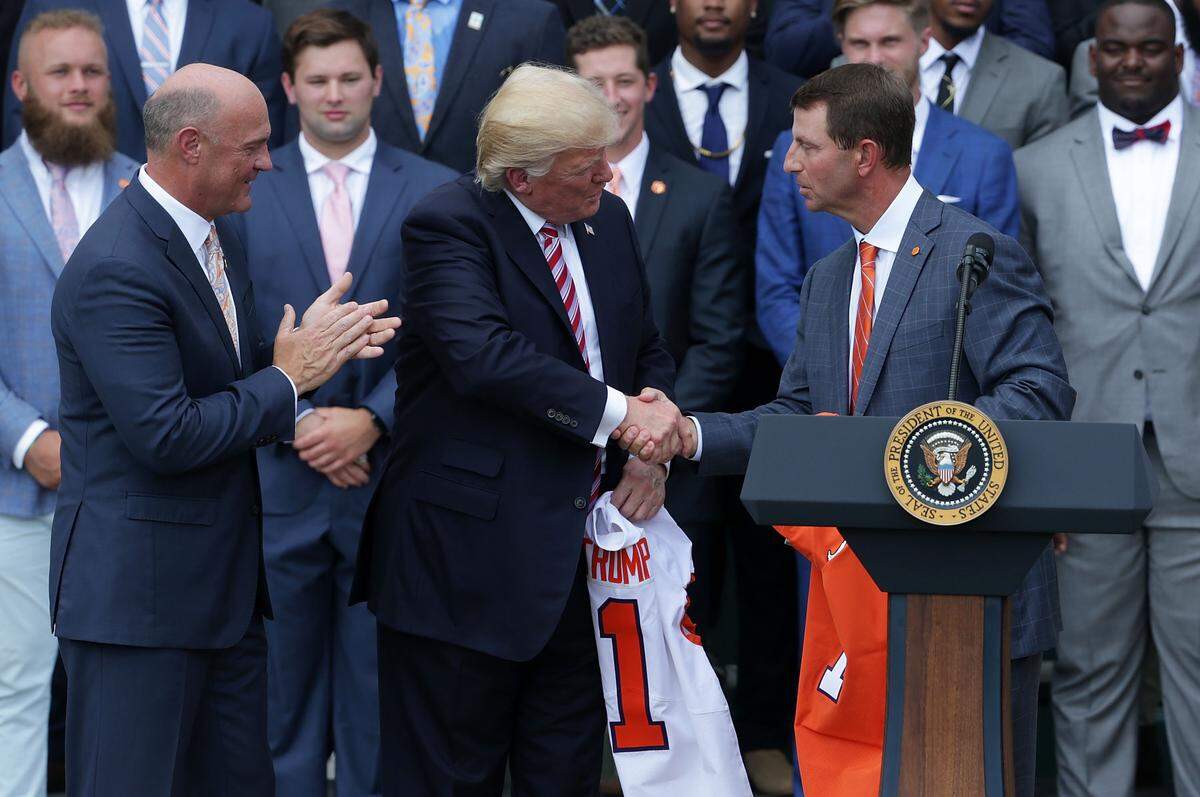 Clemson University President Jim Clements (L) and Clemson Tigers head coach Dabo Swinney (R) present two jerseys, one for President Donald Trump (2nd L) and one for his son Barron, during a South Lawn event at the White House June 12, 2017 in Washington, DC. President Trump hosted the team to honor 2016 NCAA Football National Championship.