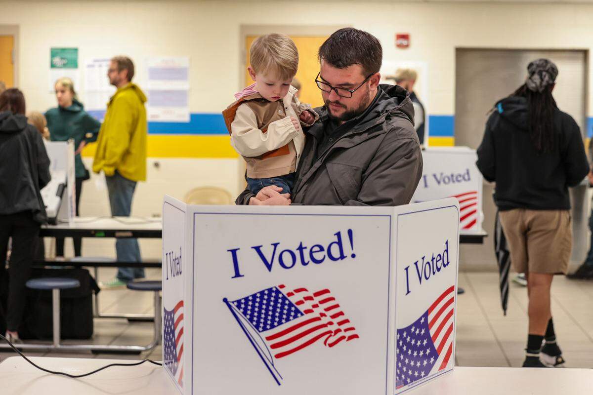 Oliver Mandeville, 2, watches as his dad, Matt Mandeville, casts his ballot at Hand Middle School on Tuesday, Nov. 5, 2024.