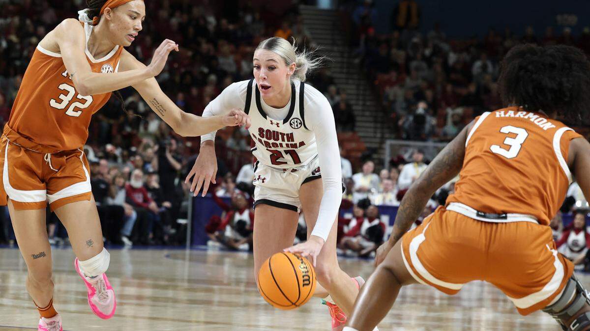 University of South Carolina’s Chloe Kitts (21) drives through Texas’ Ndjakalenga Mwenentanda (32) and  Rori Harmon (3) during the second half of action in the SEC Tournament at the Bon Secours Wellness Arena in Greenville on Sunday, March 9, 2025.
