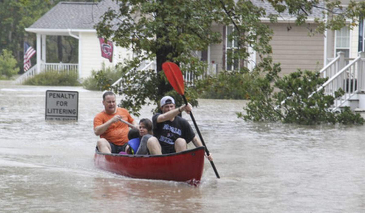 John Wienges, front, and Will Lenski paddle a canoe with Angela and Logan Smith, 7, who they rescued from their flooded house on Timberlane Drive near Gills Creek. The river flooded homes along Timberlane Drive and Whispering Pines Circle caused by heavy rains from Hurricane Joaquin on Oct. 4, 2015.