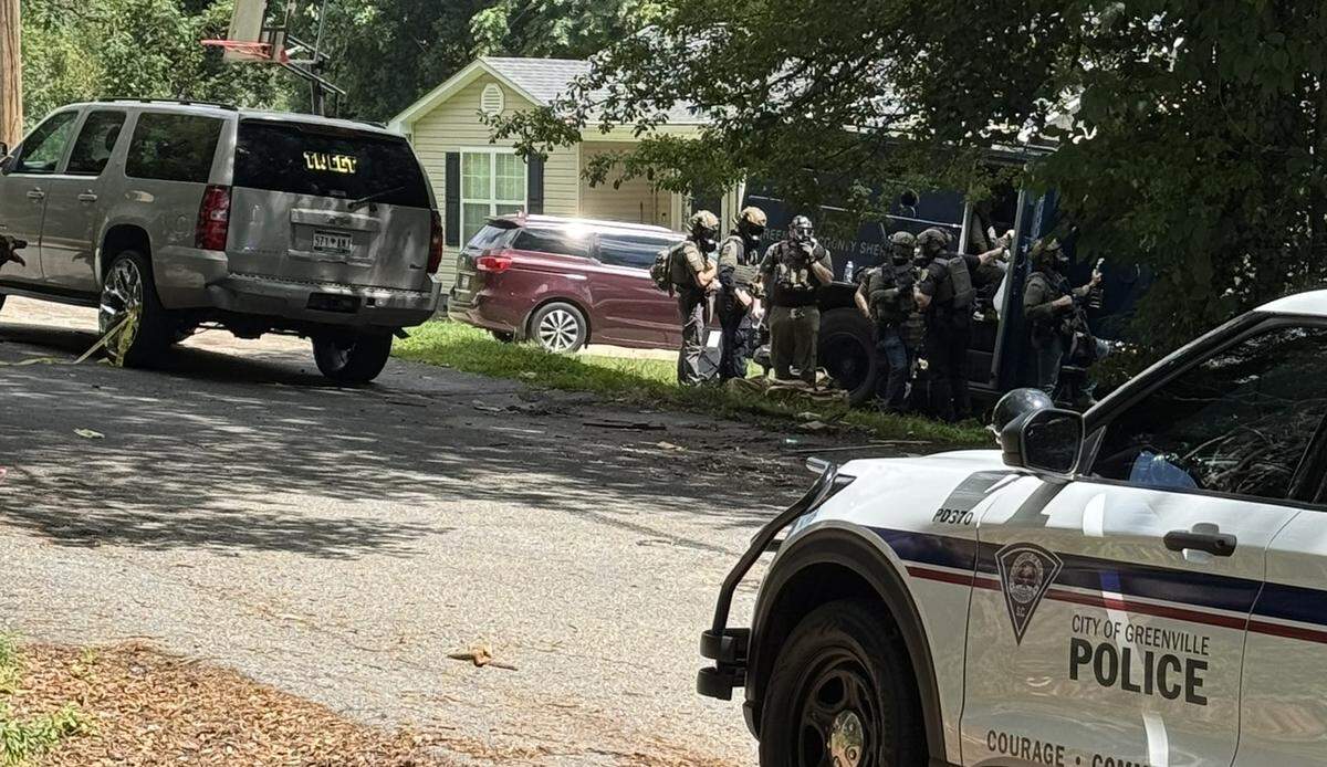 Law enforcement officers respond to a standoff with a man wanted on a murder charge and other crimes.