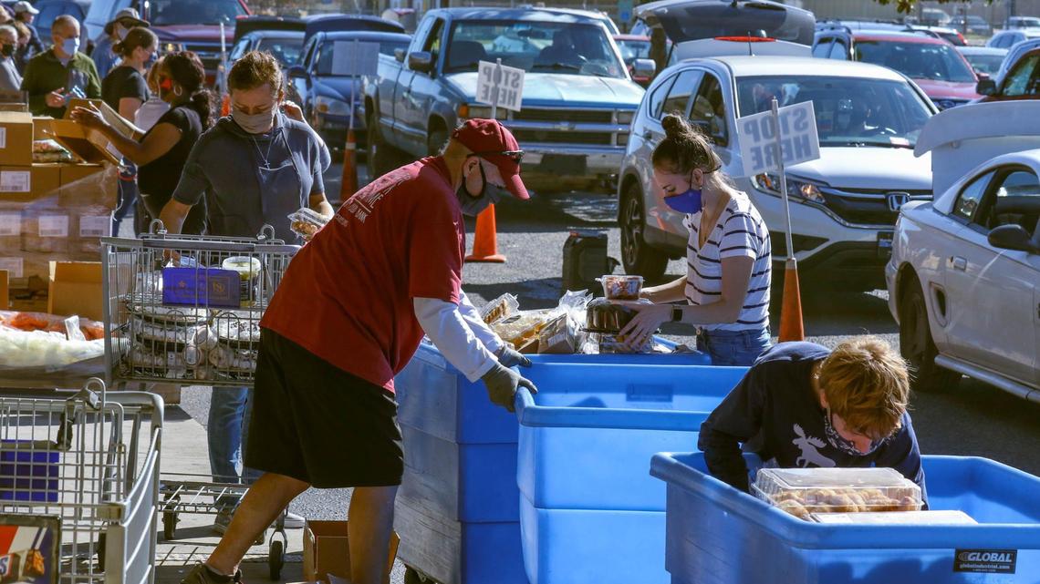 Volunteers gather food items to place in people’s cars as they drive through the line for the Harvest Hope Food Bank. The line stretched down Shop and South Beltline Roads for a mile as people wait in line for more than two hours to receive food donations on Monday, Nov. 22, 2020.