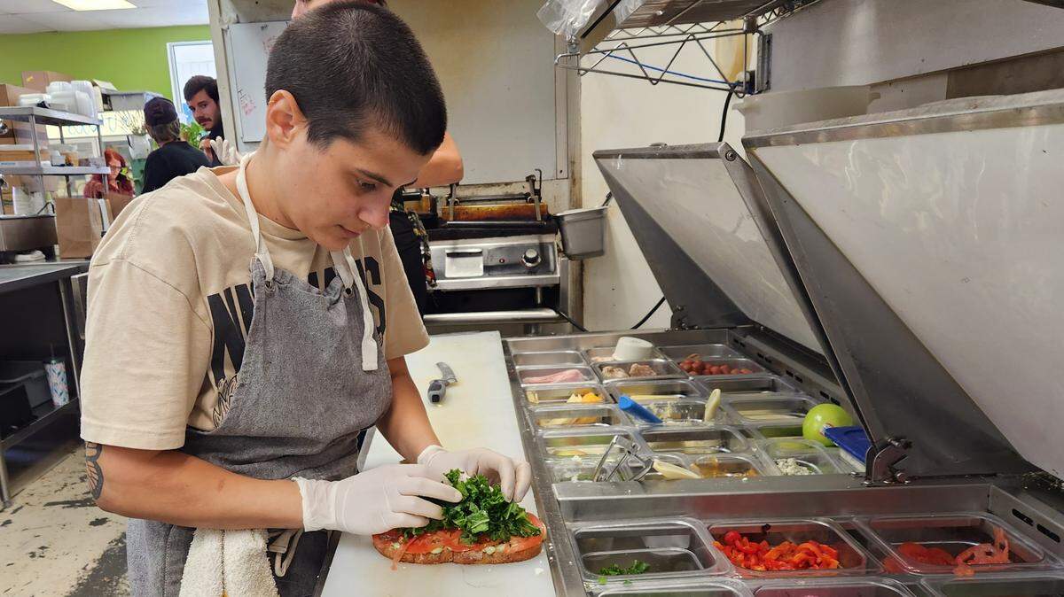 Crave Artisan Market’s T Adams makes a sandwich during a recent lunch shift at the restaurant.