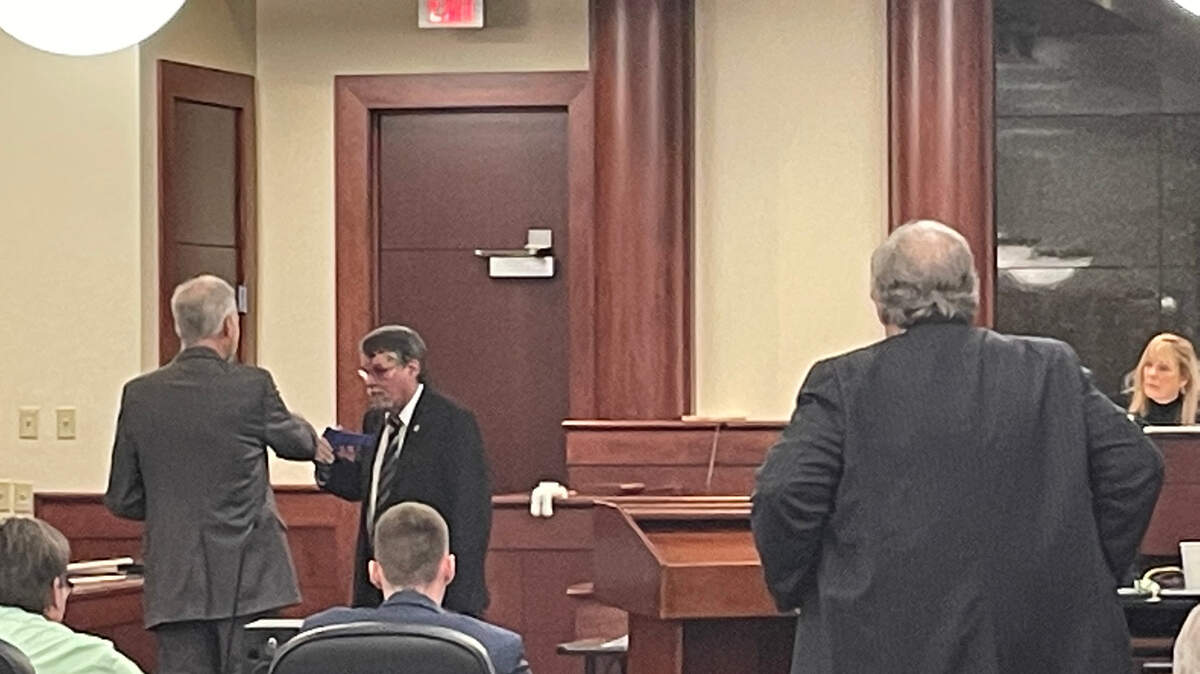 Blood splatter expert Steven Derrick shows prosecutor Shawn Graham the position a gun might have been held in when William Holland died. Dr. Adam Lazzarini is on trial in the death.