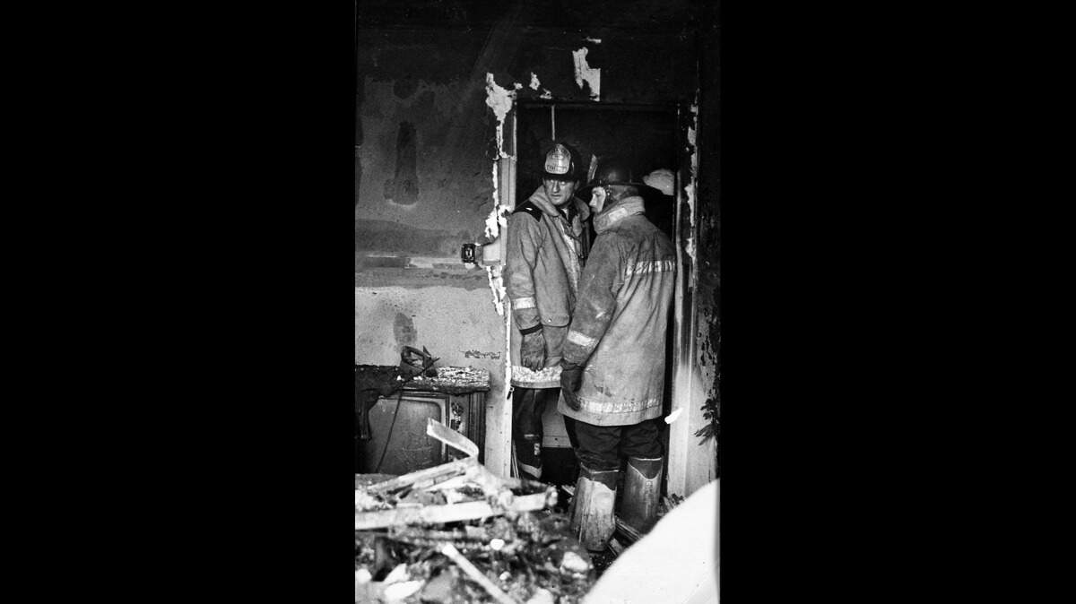 Cox (left) standing in the aftermath of a structure fire in the late 1970s.