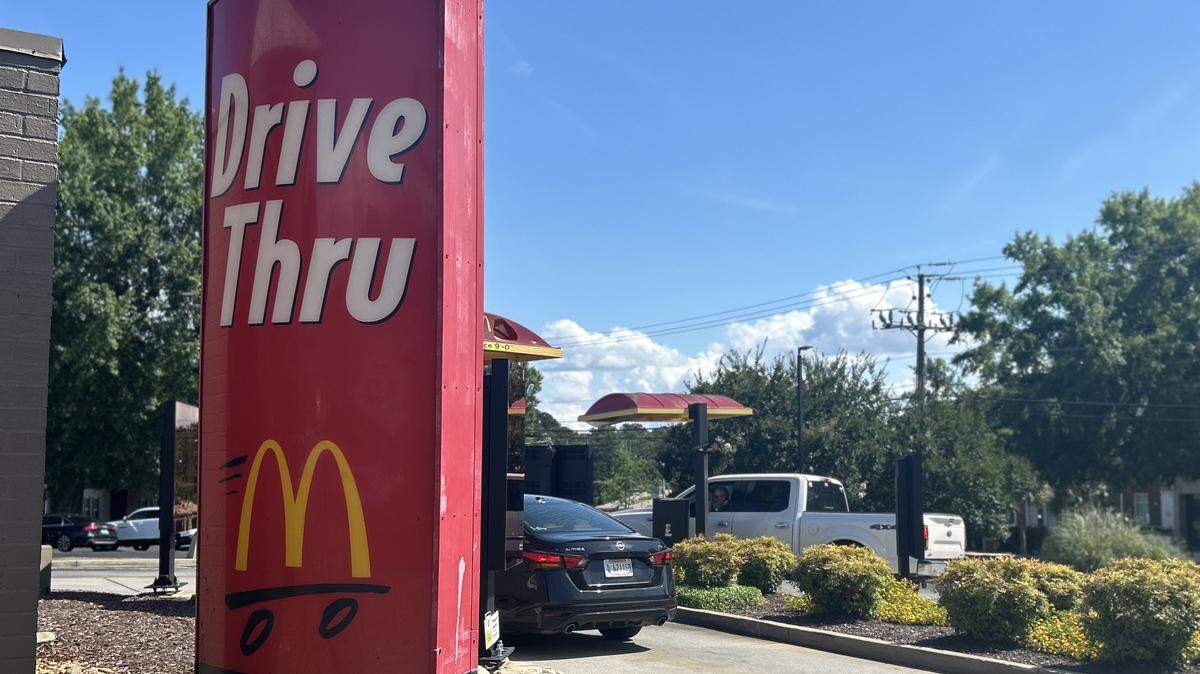 McDonald’s drive-through sign with a few cars in line to place orders.