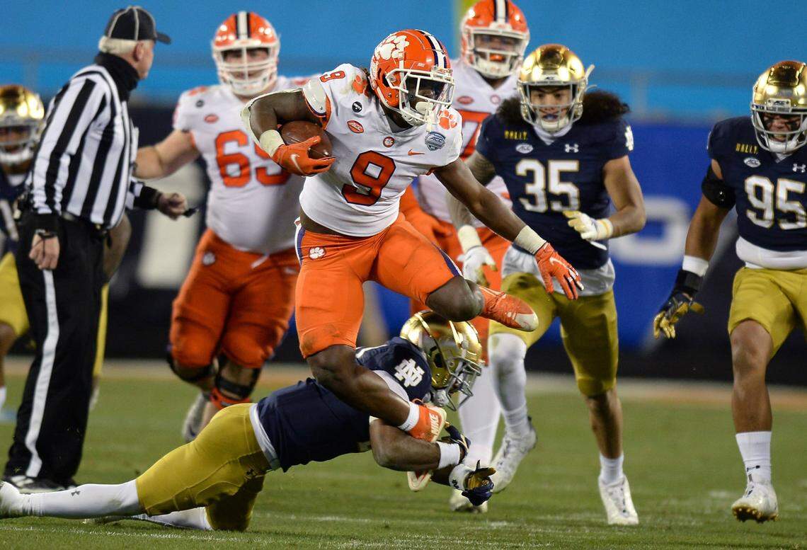 Clemson Tigers running back Travis Etienne leaps over a Notre Dame defender during third quarter action of the ACC Championship game. Clemson defeated Notre Dame 34-10 to win the championship at Bank of America Stadium in Charlotte, NC on Saturday, December 19, 2020.