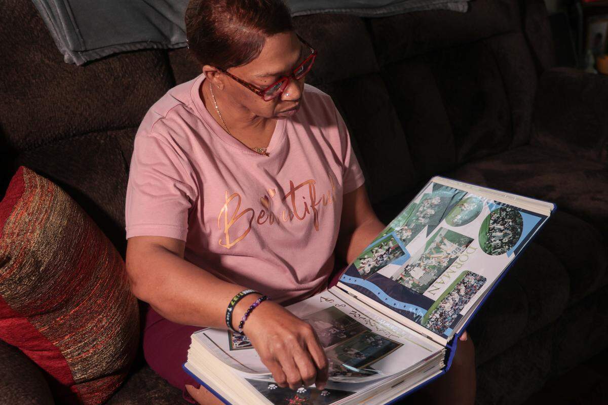 Jacqueline Summers looks through scrapbooks of her son, Demetris Summers, that include pictures and more from when he played at Lexington High School. Those memories take up a whole shelf in her living room.