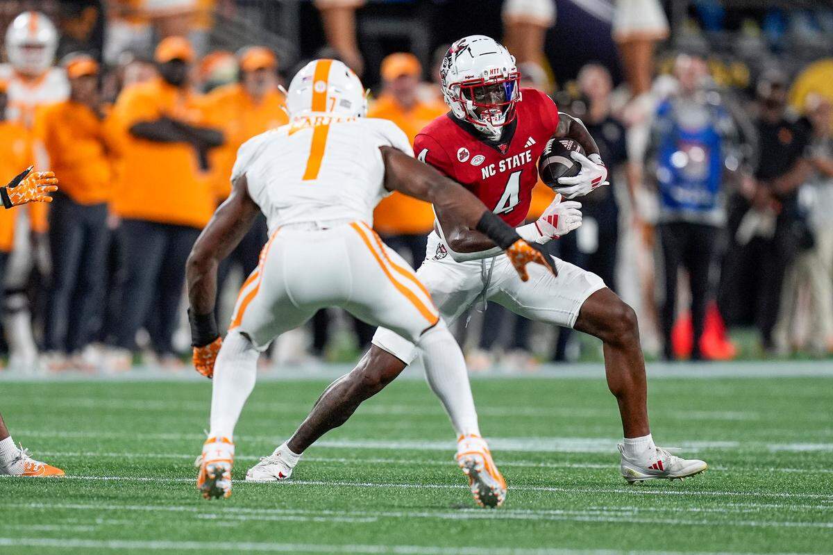Sep 7, 2024; Charlotte, North Carolina, USA; North Carolina State Wolfpack wide receiver Dacari Collins (4) runs with the ball as Tennessee Volunteers defensive back Rickey Gibson III (1) defends during the first quarter at the Dukes Mayo Classic at Bank of America Stadium.