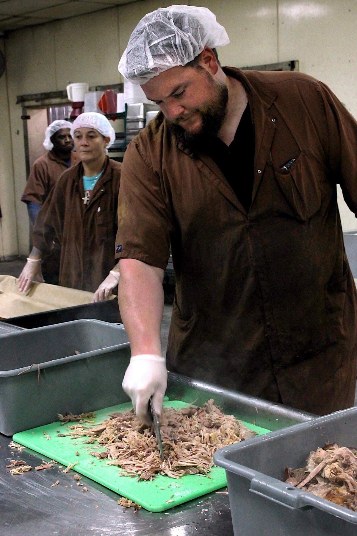 A worker chops pork barbecue at Maurice’s Piggie Park BBQ. Oct. 11, 2023