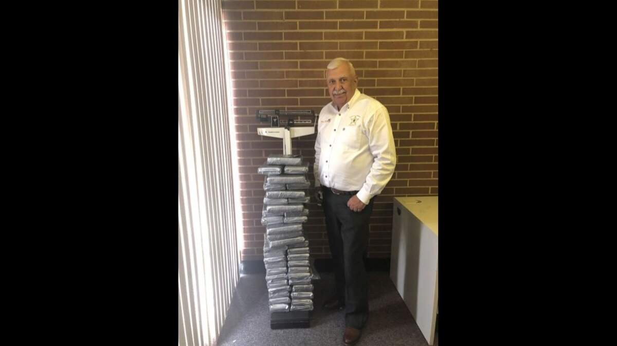 Lincoln County Sheriff Bill Beam stands next to more than 100 pounds of cocaine seized in a traffic stop.