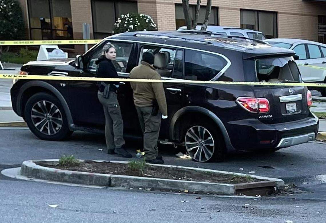 Law enforcement officers investigate a vehicle that was hit by gunfire.